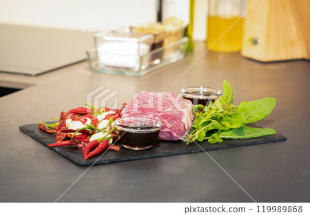Raw Beef and herb ingredients, basil leaf, garlic, chilli, sauces are prepared on a black stone, slate plate for next cooking process in the Thai food menu, Stir-fried beef basil. 119989868