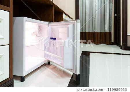 Refrigerator fridge mini size under the table counter with wooden desk beside it in hotel delux room. Refrigerator fridge mini size under the table counter with wooden desk beside it in hotel delux room. 119989933