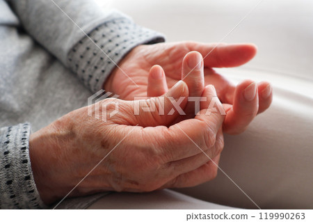 Senior woman's hands touching her fingers on her lap Senior woman's hands touching her fingers on her lap 119990263