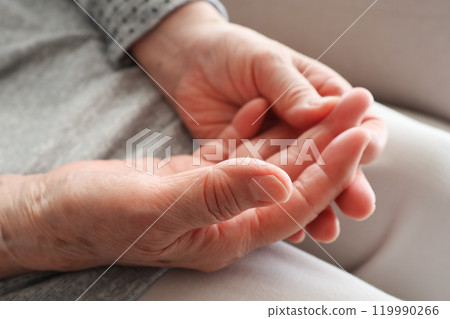 Senior woman's hands touching her fingers on her lap 119990266