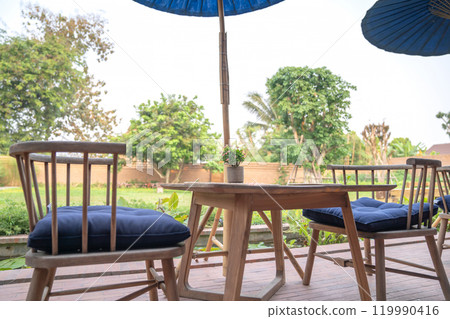 Thailand Northern traditional modern combination wood table and chair set with wicker plate on it in the garden blur background Thailand Northern traditional modern combination wood table and chair set with wicker plate on it in the garden blur background 119990416