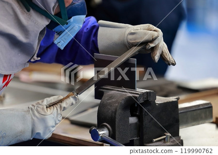 A craftsman filing a piece, removing burrs A craftsman filing a piece, removing burrs 119990762