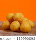 Pile of crispy breaded potato balls on a wooden surface against an orange background. Studio food photography. Snack and appetizer concept. Design for poster, banner, menu, wallpaper 119990898