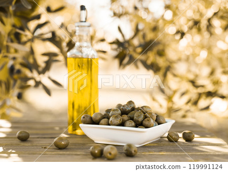 Green olives and oil on table in olive grove Green olives and oil on table in olive grove 119991124