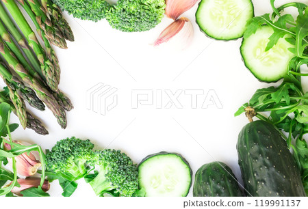 Frame of green vegetables broccoli, arugula, cucumber, asparagus and garlic on white background 119991137
