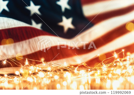 Sparkles with lights in soft focus and American flag on the background. July forth celebration. The Independence day backdrop. Abstract minimalistic wallpaper with space for text.  119992069