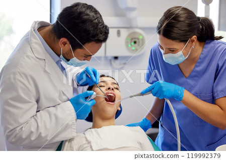 Dentist, team and oral care with patient for healthcare, wellness and teeth whitening in practice. Woman, dental professional and PPE with tools for consultation, cleaning and filling on chair 119992379