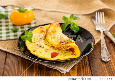 fried omelette with sweet pepper and vegetables in a plate on a wooden table fried omelette with sweet pepper and vegetables in a plate on a wooden table 119992533