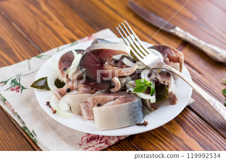lightly salted mackerel with onions and spices on a wooden table lightly salted mackerel with onions and spices on a wooden table 119992534