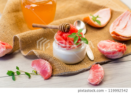 homemade sweet yogurt in a glass jar with pieces of red ripe grapefruit and honey, on a wooden table homemade sweet yogurt in a glass jar with pieces of red ripe grapefruit and honey, on a wooden table 119992542
