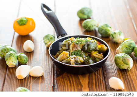 Brussel sprouts cooked with vegetables and spices, on a wooden table Brussel sprouts cooked with vegetables and spices, on a wooden table 119992546