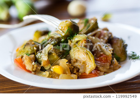 Brussel sprouts cooked with vegetables and spices, on a wooden table 119992549