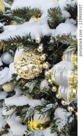 Branches of Christmas tree with beautiful decorations covered with snow 119993087