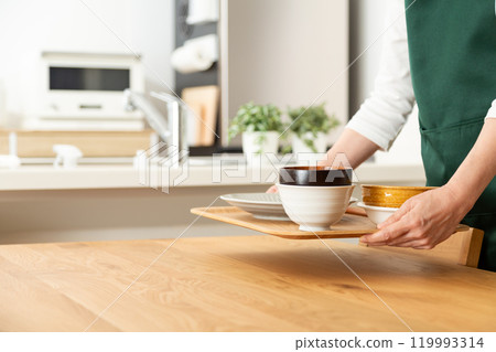 一名中高級婦女正在清理盤子並端著托盤 119993314