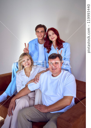 family, middle-aged husband and wife, young son and teenage daughter, sitting on sofa, studio photo shoot family, middle-aged husband and wife, young son and teenage daughter, sitting on sofa, studio photo shoot 119993440