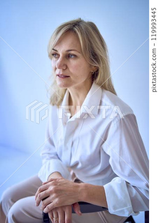 portrait of a stylish blonde middle-aged woman in a white blouse and beige pants portrait of a stylish blonde middle-aged woman in a white blouse and beige pants 119993445