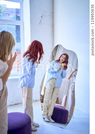a middle-aged mother and her teenage daughter fix their hair in front of the mirror a middle-aged mother and her teenage daughter fix their hair in front of the mirror 119993636