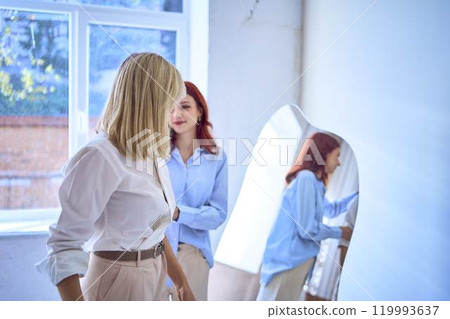 a middle-aged mother and her teenage daughter fix their hair in front of the mirror a middle-aged mother and her teenage daughter fix their hair in front of the mirror 119993637