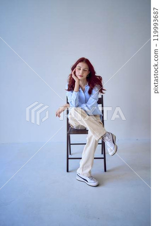 portrait of a beautiful teenage girl with red hair sitting on a chair on a white background portrait of a beautiful teenage girl with red hair sitting on a chair on a white background 119993687