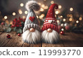 Two adorable gnome decorations with tall knitted hats and fluffy white beards. One wears a gray hat with a red heart, and the other a red hat with white hearts. Cozy holiday ambiance. 119993770
