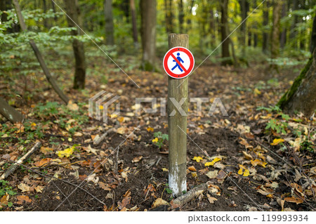 A round sign prohibiting entry into the forest. A no walking sign is posted on a wooden stake on nature background. High quality photo A round sign prohibiting entry into the forest. A no walking sign is posted on a wooden stake on nature background. High quality photo 119993934