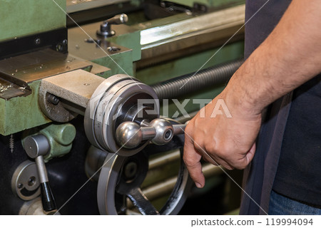 The machine operator working with lathe machine. 119994094