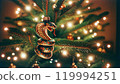A colorful snake ornament decorates a festive Christmas tree, surrounded by glowing lights and traditional decorations, adding a unique touch to the holiday ambiance. 119994251