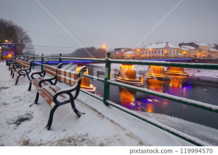 uzhhorod, ukraine - 26 DEC 2016: urban scenery with riverside at dawn. architecture landmark. winter holidays cityscape. light of downtown reflecting in the water. famous place 119994570