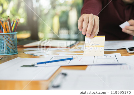 UX or UI designers designing on digital tablet and smartphone application layout prototype project. UX or UI designers designing on digital tablet and smartphone application layout prototype project. 119995170
