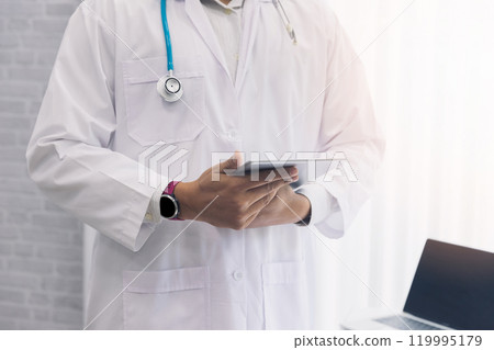 Doctor standing with stethoscope and holding tablet computer. Technology and medical concept. Doctor standing with stethoscope and holding tablet computer. Technology and medical concept. 119995179