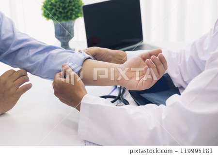 The doctor rolls up the patient's sleeve to measure blood pressure or give an injection. The doctor rolls up the patient's sleeve to measure blood pressure or give an injection. 119995181