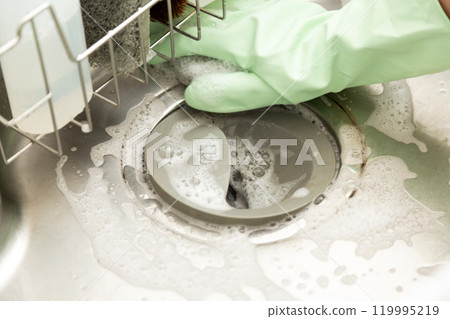 The hands of a middle-aged to senior woman washing the kitchen sink 119995219