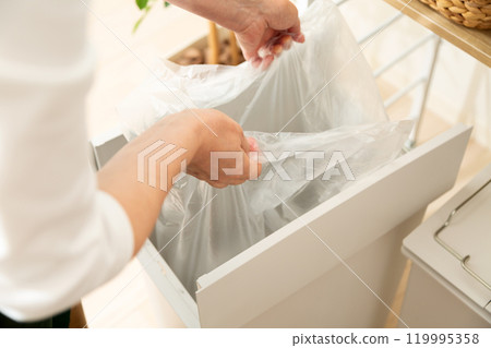 The hands of middle-aged to senior women sorting and throwing away recyclable waste 119995358