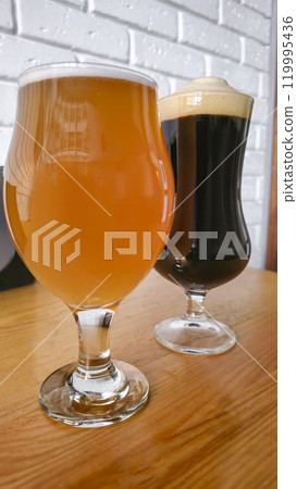 Glasses with light and dark beer on a dark background. Nuts and crackers 119995436