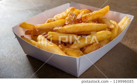 a white paper box filled with golden brown French fries a white paper box filled with golden brown French fries 119996085