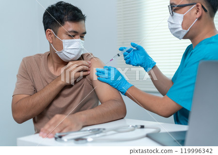 Doctor Administering Vaccine Injection to Patient's Arm in Medical Setting 119996342