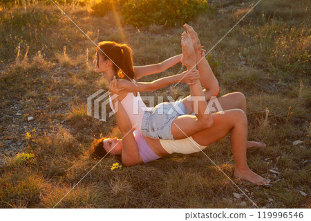 Training of female gymnasts in bright rays of sunset. Fly yoga Training of female gymnasts in bright rays of sunset. Fly yoga 119996546