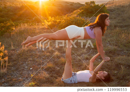 Young beautiful women doing aerial gymnastics against the backdrop of the sunset 119996553