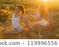 Young beautiful women gymnasts doing exercises on the grass against the sunset 119996556