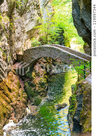 Old small stone bridge over river at Gorges de l'Areuse, Switzerland 119997344