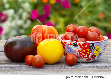 Variety of tomatoes, big and small, on the wooden table in the garden. 119998213