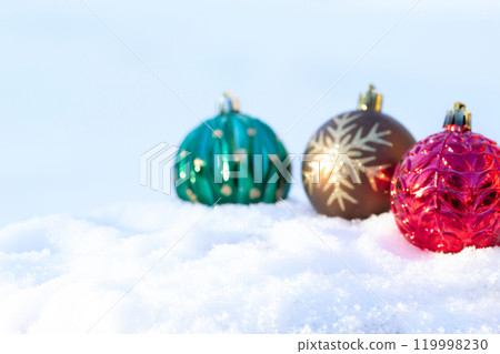 Red, brow and green christmas bulbs with ornament are on the snow. Red, brow and green christmas bulbs with ornament are on the snow. 119998230
