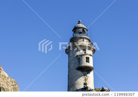 Aniva - The abandoned lighthouse in the Sakhalin Island, Korsakov district, Russia. Pacific ocean. The abandoned lighthouse Island Blue sea. Beautiful view. Blue sky and blue Pacific ocean. 119998307
