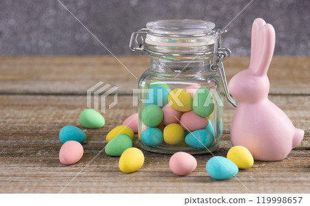 Easter composition with pink bunny and a jar with colorful candies. 119998657