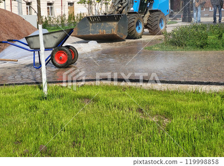 Preparing for the landscaping of the park, there is a sandbarrow and a small excavator Preparing for the landscaping of the park, there is a sandbarrow and a small excavator 119998858