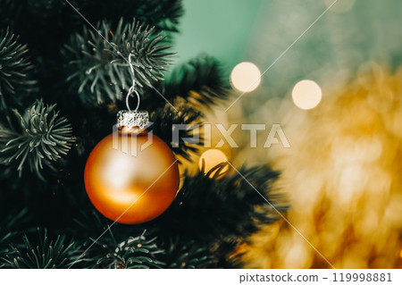 Christmas ball hanging on tree, gold and green xmas background, detail on golden Christmas bauble 119998881