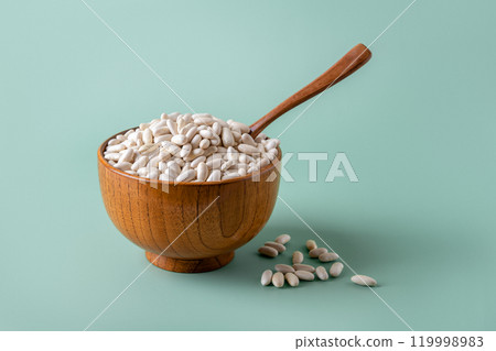 White beans in a wooden bowl over pastel mint background.  119998983