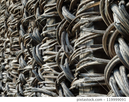 A close view of an old rustic fence made from intertwined natural materials A close view of an old rustic fence made from intertwined natural materials 119999091