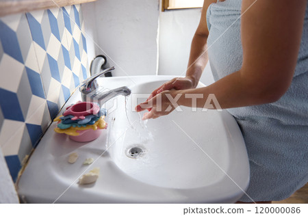 Woman washing hands in bathroom with colorful decor 120000086