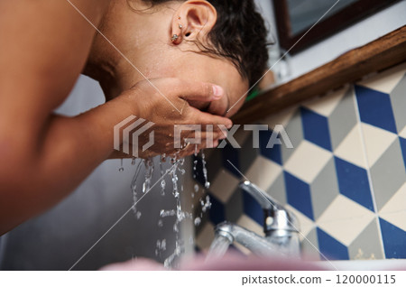 Woman washing her face with water at a bathroom sink 120000115